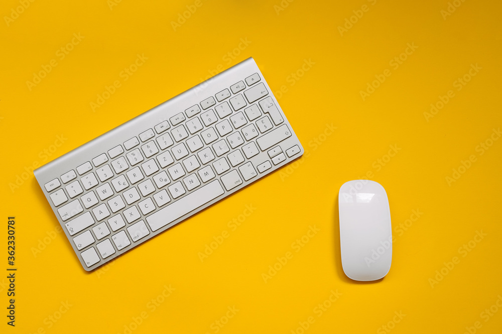 Wireless white keyboard and mouse on clean yellow background. Wireless white keyboard and mouse on clean yellow background.