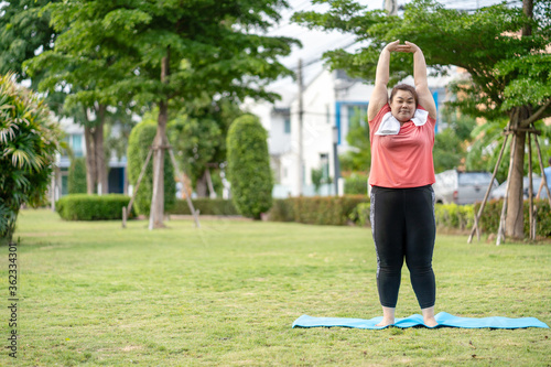 new normal concept,Young woman is happy to motivation exercise or yoga outdoor in the garden to control or lose weight.Obese fat woman have intention exercise to lose weight and build strong health.