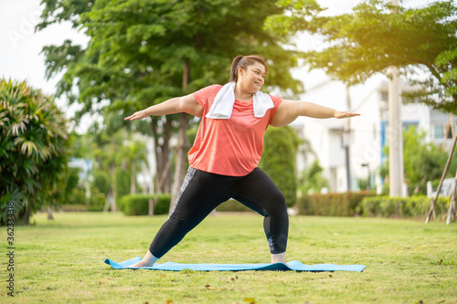 new normal concept,Young woman is happy to motivation exercise or yoga outdoor in the garden to control or lose weight.Obese fat woman have intention exercise to lose weight and build strong health.