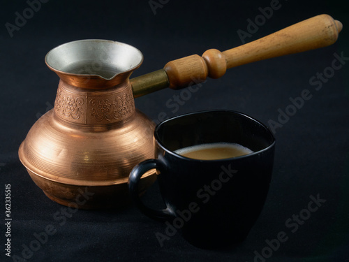 Freshly brewed Arabic coffee and copper cezve on black velvet