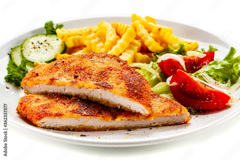 Breaded fried pork chop, French fries and vegetables on white background
Breaded fried pork chop, French fries and vegetables on white background