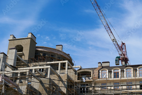 modern building under construction, plastered walls and scaffolding, construction crane