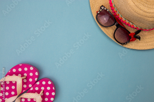 beach accessories on a blue background, beach slippers, hat, goggles. Copy space, text space. Holidays at sea