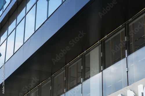 facade of a modern building on a bright Sunny day, blue sky and clouds reflecting in a glass, beautiful exterior of the new building © soleg