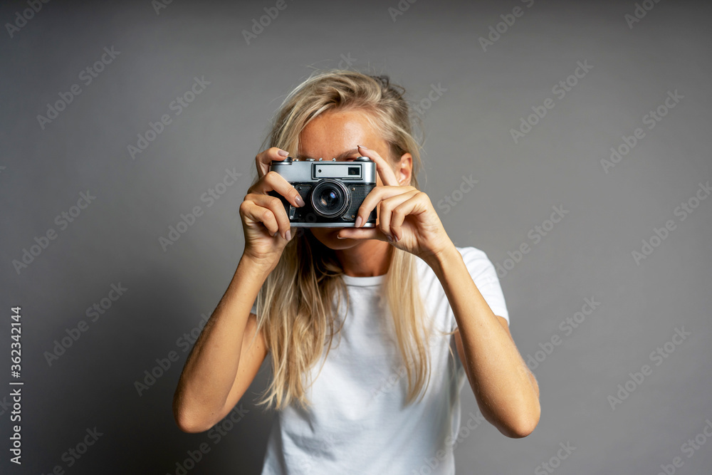 Blond female photographer takes a picture with a vintage camera. Blond female photographer takes a picture with a vintage camera.