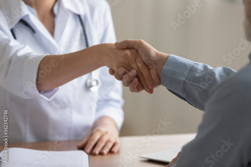 Billede på lærred Crop close up of male patient shake hand get acquainted greeting with female doc