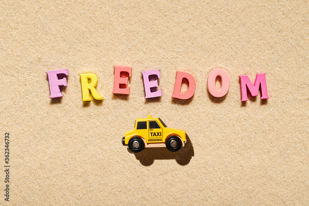 Toy yellow taxi car ride on the colorful letters of word freedom on ...