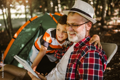 Boy camping with grandfather in the forest.