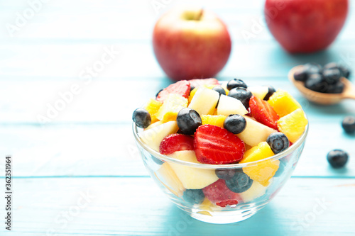 Salad with fresh fruits and berries on blue wooden background