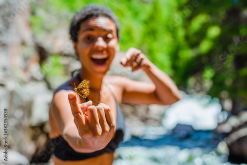 Canvas Print BIPOC woman holding an orange butterfly