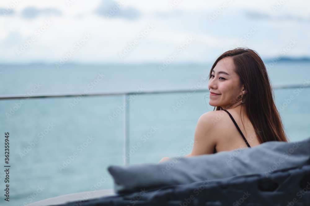A beautiful young asian woman sitting and looking at the sea and blue sky view