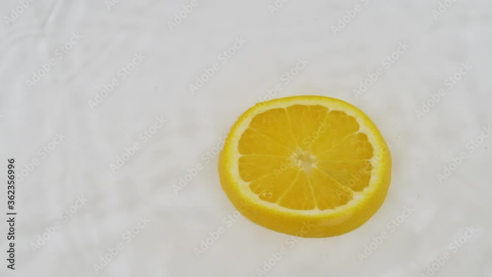 Fall of yellow slice of orange in white water. Slow motion. Fall of yellow slice of orange in white water. Slow motion.