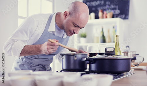 Handsome man is cooking on kitchen and smiling