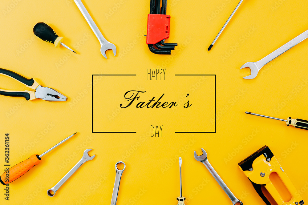 Tools top view on yellow background. Father's day card with tools. Plier, open wrenches, screwdrivers and staple gun in a cirlce.