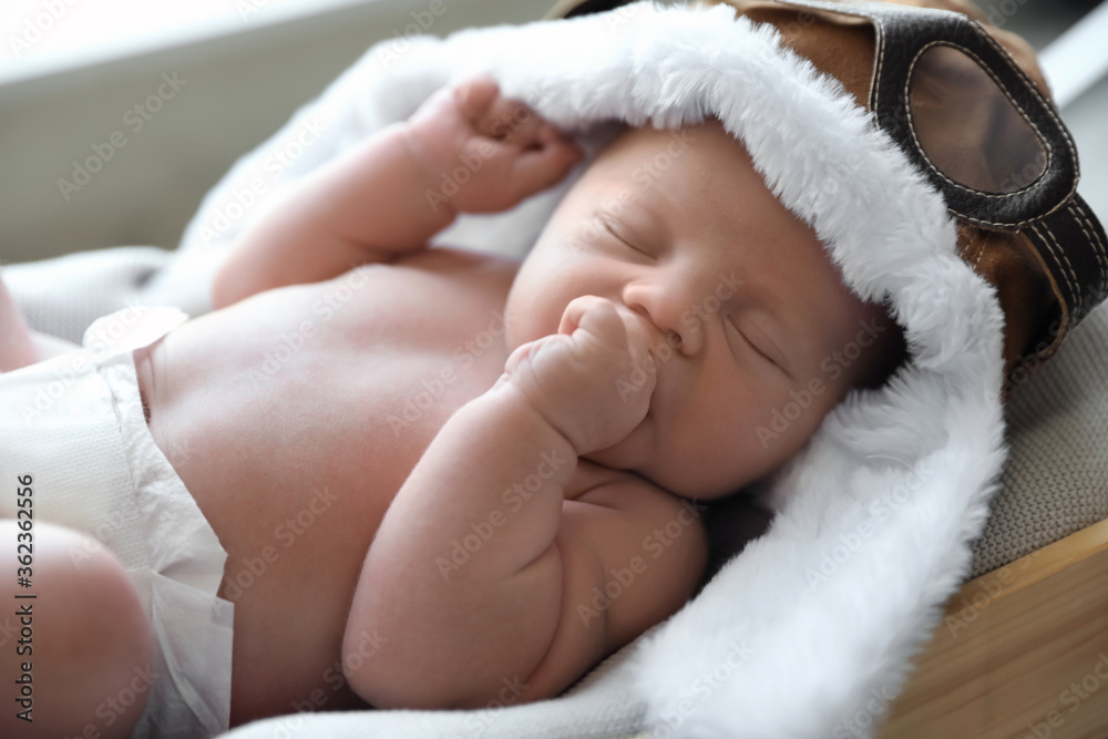 Cute newborn baby in aviator hat sleeping on blanket, closeup Cute newborn baby in aviator hat sleeping on blanket, closeup