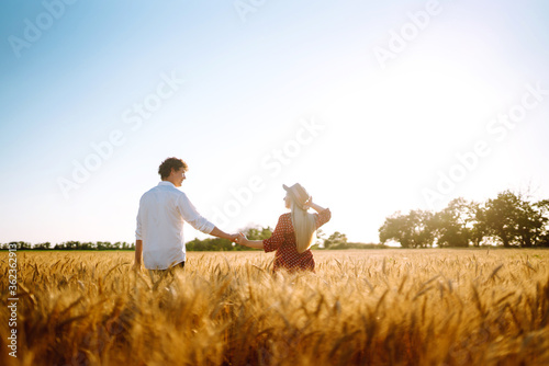 Couple having fun and enjoying relaxation in a wheat field. Teenage girlfriend and boyfriend kissing and hugging. The concept of youth, love and lifestyle.