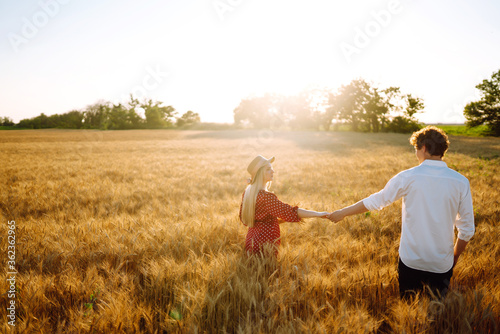 Couple having fun and enjoying relaxation in a wheat field. Teenage girlfriend and boyfriend kissing and hugging. The concept of youth, love and lifestyle.