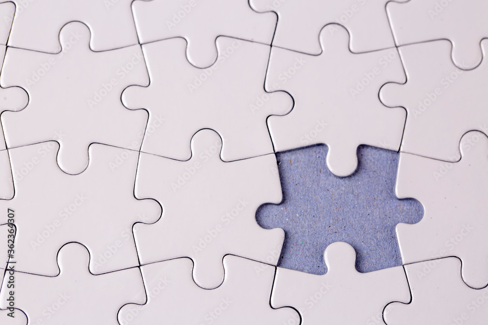 Missing jigsaw puzzle pieces. Business concept. Fragment of a folded white jigsaw puzzle and a pile of uncombed puzzle elements against Missing jigsaw puzzle pieces. Business concept. Fragment of a folded white jigsaw puzzle and a pile of uncombed puzzle elements against