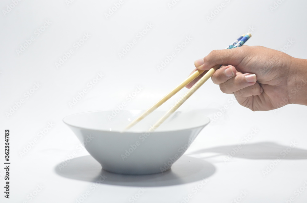 Hand using chop stick against white bowl on isolated white background Hand using chop stick against white bowl on isolated white background