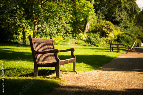 Beautiful old empty wooden bench in garden. Relax peaceful in the park © Anna