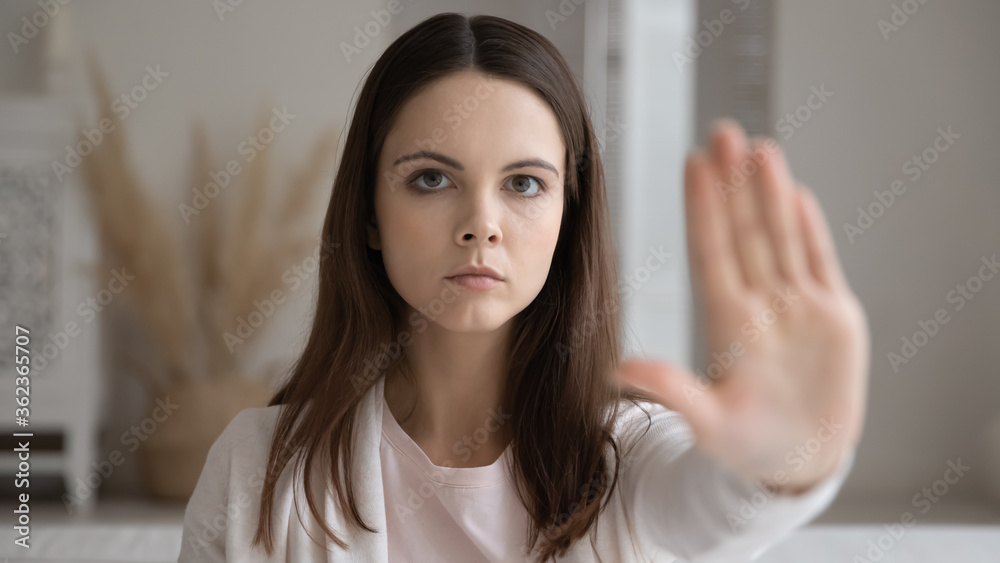 Head shot portrait confident young woman showing stop or defense gesture close up, looking at camera, serious focused girl protesting against domestic violence, abuse, gender discrimination