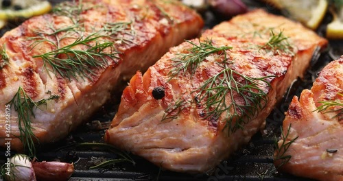 Grilled salmon fillets on a grill plate drizzled with lemon juice
