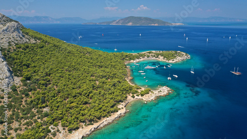 Aerial drone photo of beautiful exotic turquoise sea rocky Mediterranean island forming a blue lagoon visited by sail boats and yachts © aerial-drone