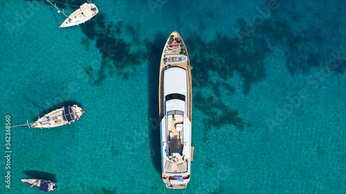Aerial drone photo of yacht anchored in popular bay and beach of Super Paradise, Mykonos island, Cyclades, Greece