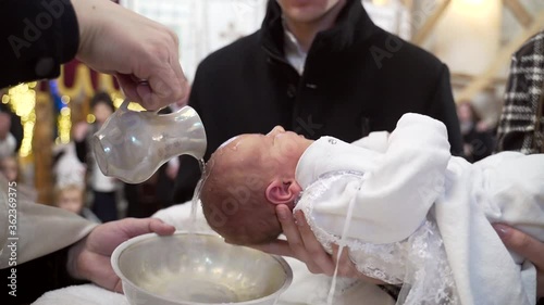 Newborn baby baptism in Holy water. Baptism in the font. Sacrament of baptism. Child and God. Christening candle Holy water font. The priest baptize. in the church