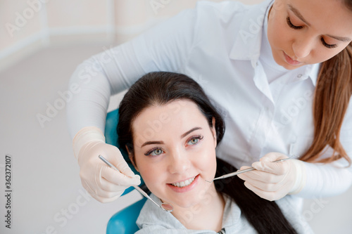 Patient in dental chair. Dentist's hands in gloves work with a dental tools. Beautiful young woman having dental treatment at dentist's office.