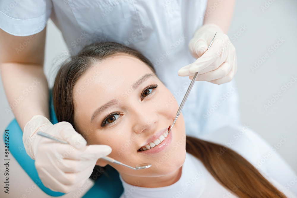 Patient in dental chair. Dentist's hands in gloves work with a dental tools. Beautiful young woman having dental treatment at dentist's office. Patient in dental chair. Dentist's hands in gloves work with a dental tools. Beautiful young woman having dental treatment at dentist's office.
