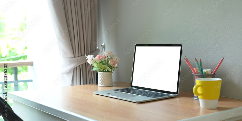 Blank screen computer laptop is putting on a wooden working desk in the living room. Blank screen computer laptop is putting on a wooden working desk in the living room.