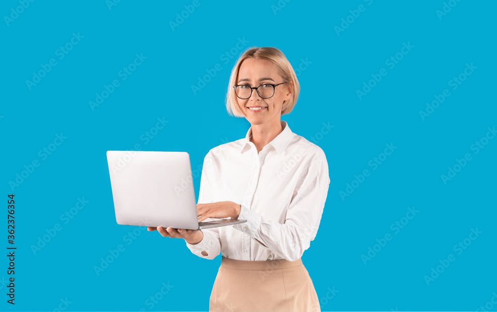 Online work. Successful office employee holding laptop computer on blue background Online work. Successful office employee holding laptop computer on blue background