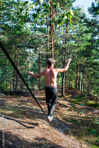 young man doing slackline rodeo in forrest outside sports activities, lifestyle people concept