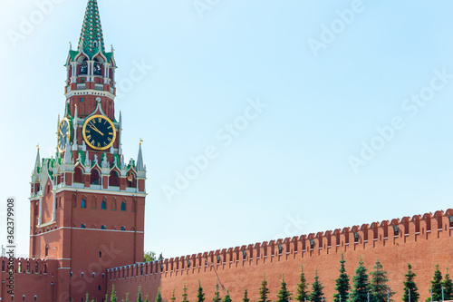 View of Spasskaya Tower and red brick wall of Moscow Kremlin on a summer morning. Clear blue sky in the background. Copy space for your text. Theme of travel in Russia.