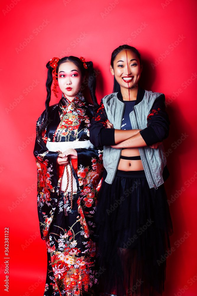 two pretty geisha girls friends: modern asian woman and traditional wearing kimono posing cheerful on red background two pretty geisha girls friends: modern asian woman and traditional wearing kimono posing cheerful on red background