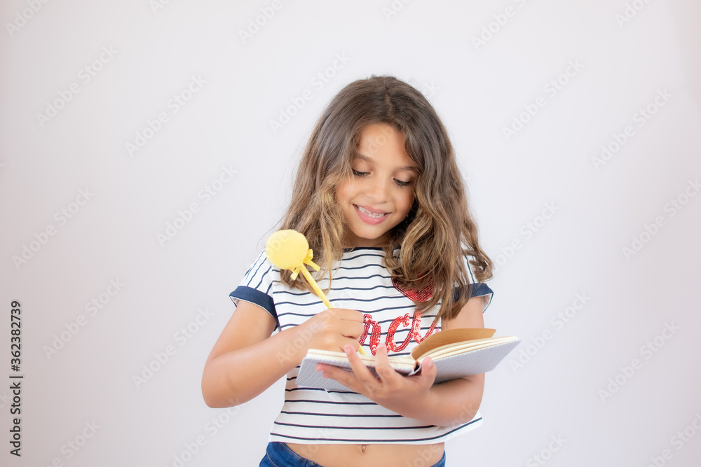 Pretty little girl in striped shirt writing in a notebook Pretty little girl in striped shirt writing in a notebook