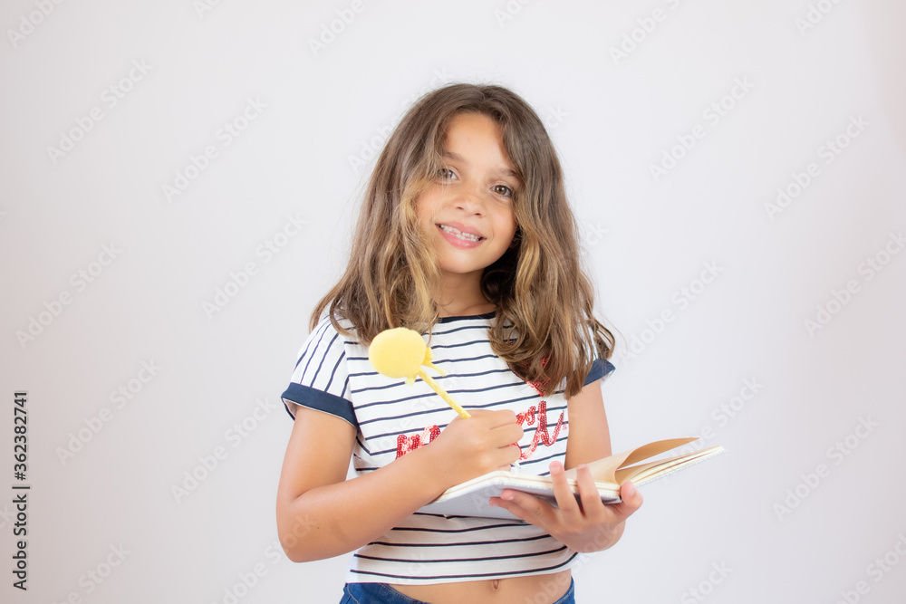Pretty little girl in striped shirt writing in a notebook Pretty little girl in striped shirt writing in a notebook