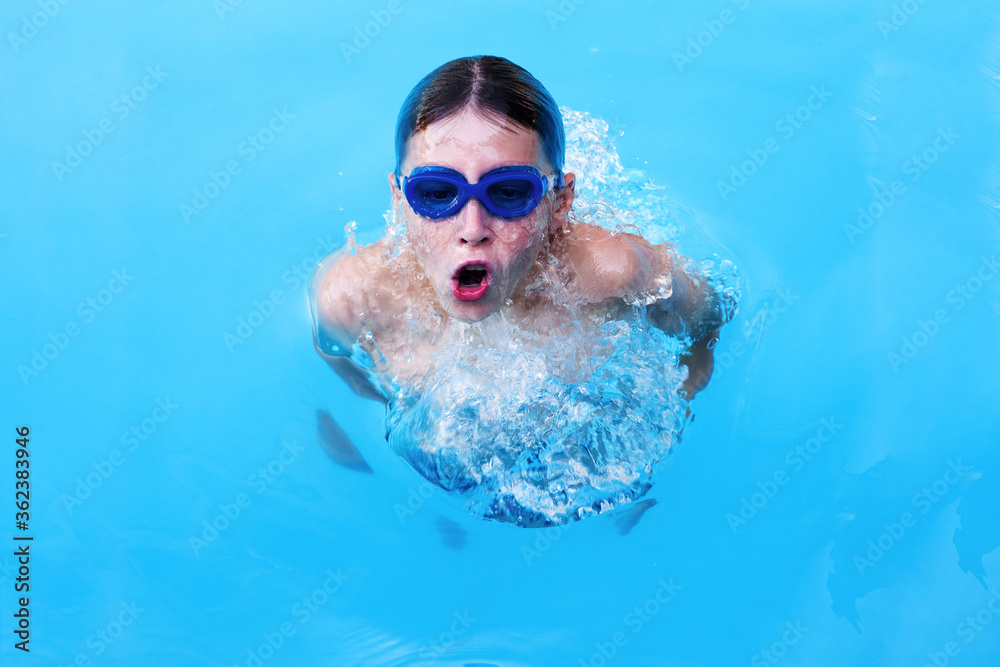 Naklejka premium Little boy athlete swims in the pool by the crawl. The concept of training and children's sports