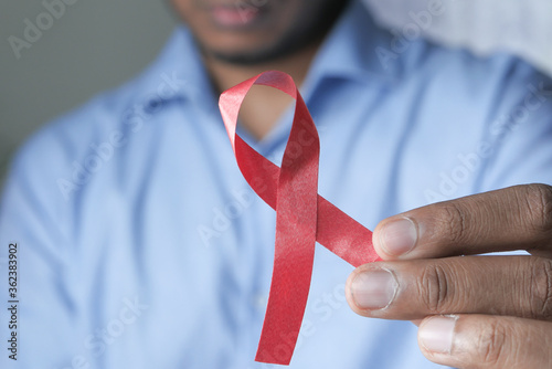 Фотография hand holding red HIV ribbon with copy space