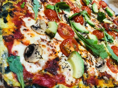 close-up of pizza with cherry tomatoes, cheese, mushrooms, avocado, lamb's lettuce and arugula