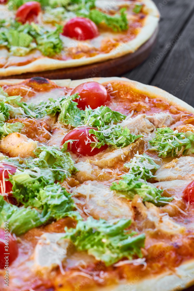 Fresh pizza with chicken, tomatoes and cheese on a dark wooden background. Close-up, selective focus