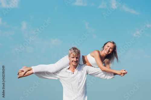 guy holds in his hands a girl in white clothes on the ocean