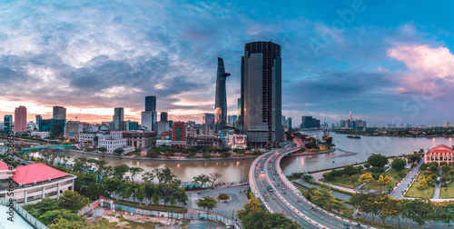 Ho Chi Minh city at sunset, Khanh Hoi bridge, yellow trail on street, the building in picture is bitexco tower, Far away is landmark 81 skyscraper