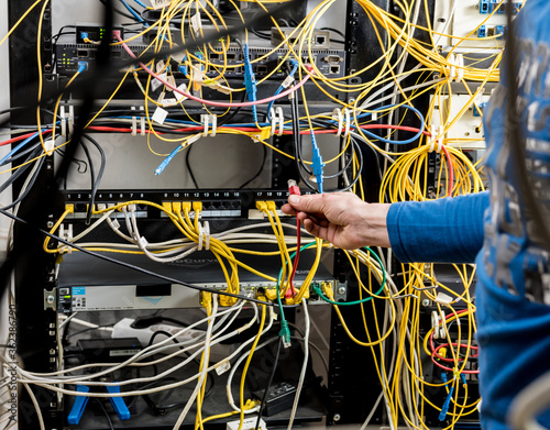 Network engineer working in server room. Connecting network cables to switches © romaset