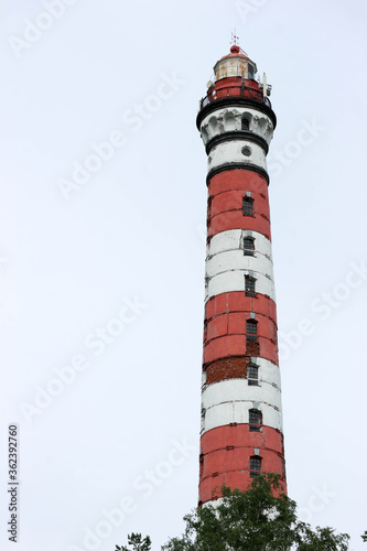 old tall Osinovetskiy lighthouse on a blue sky background on a coast of Ladoga lake