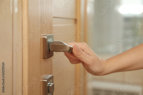 Woman opening door indoors, closeup of hand