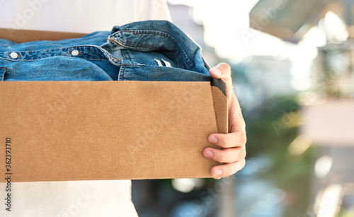 Fényképezés Man holding cardboard box with clothes inside