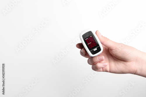 Woman holding fingertip pulse oximeter on white background, closeup. Space for text