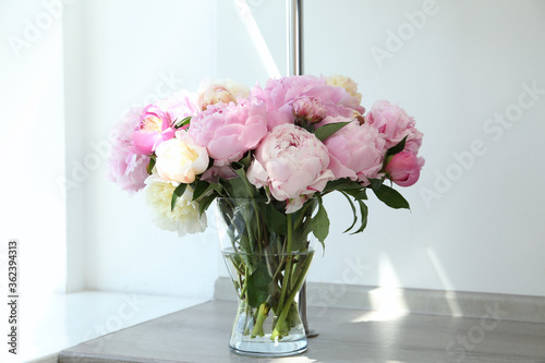 Bouquet of beautiful peonies in vase on wooden table